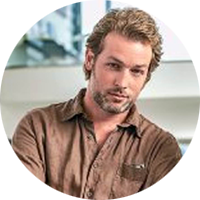 Max Winter has short, curly blonde hair and is wearing a brown button up shirt